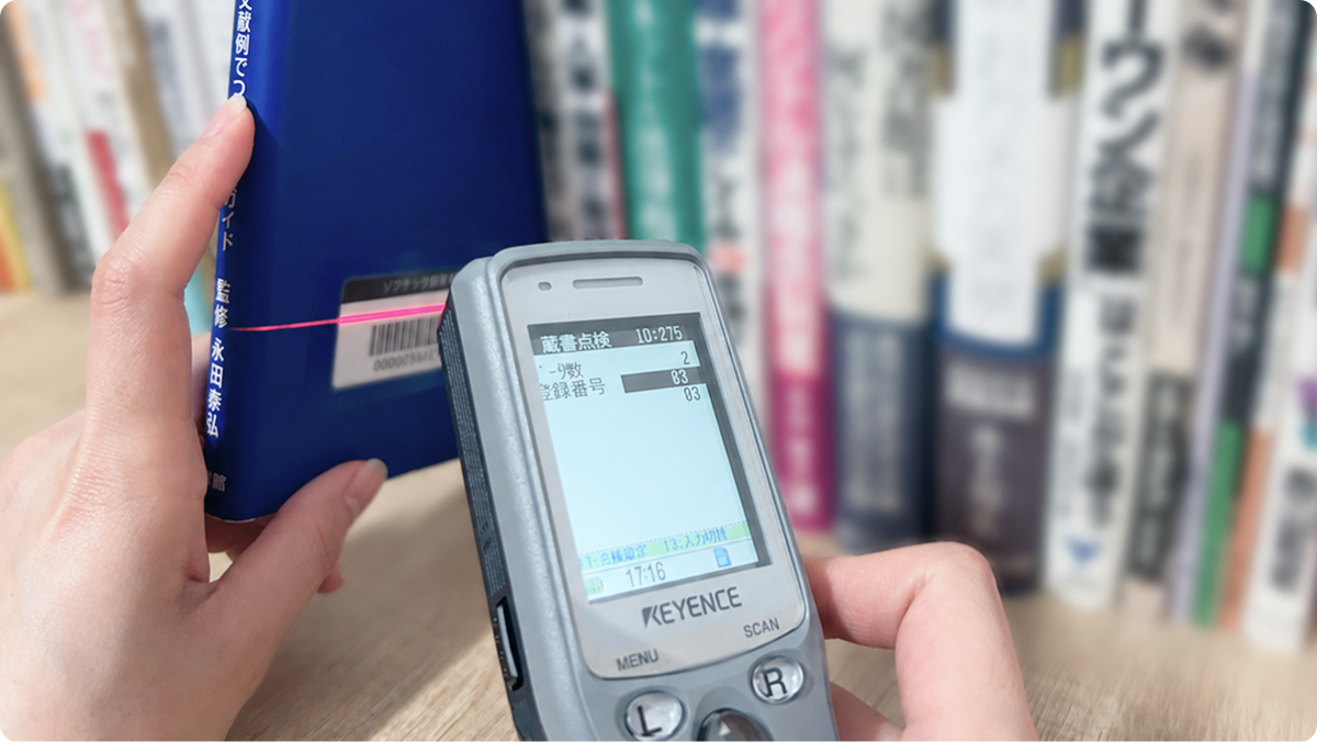 ハンディターミナルで書籍背面のバーコードを読み取る手元の写真